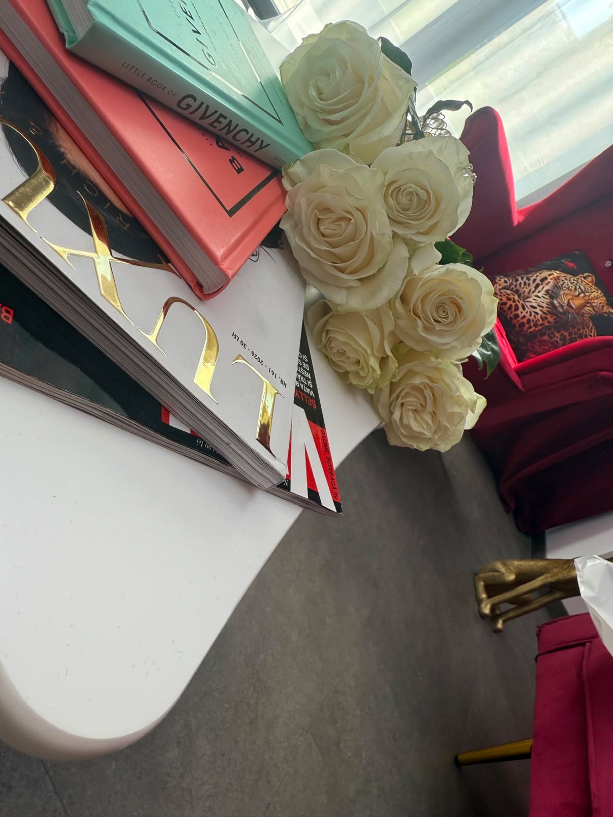 Detaliu de decor din salonul W Beauty Studio din Scala Center: trandafiri albi, cărți de modă și fotolii bordo